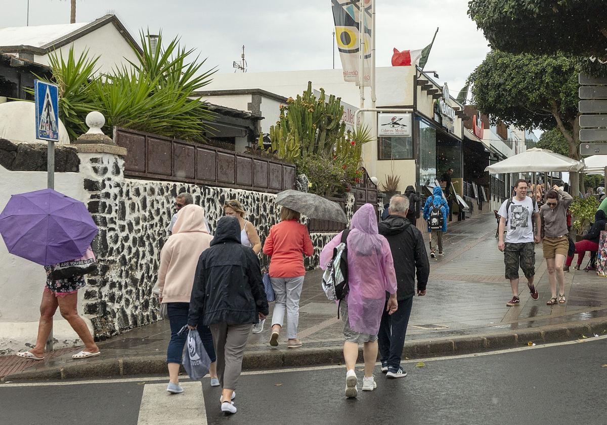 Turistas con chubasqueros y paraguas en Lanzarote.