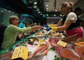 Una mujer hace la compra en la pescadería de un mercado.