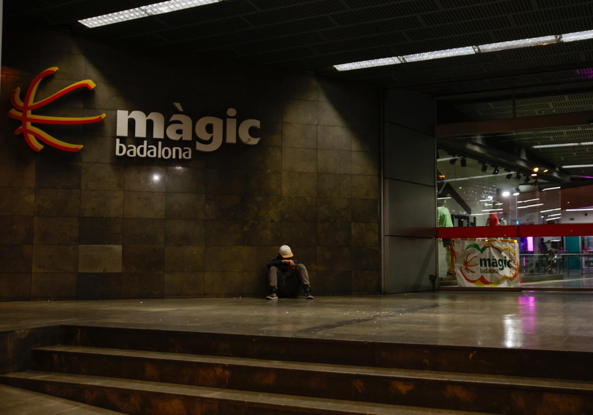 Una persona sentada en una entrada del centro comercial Màgic Badalona