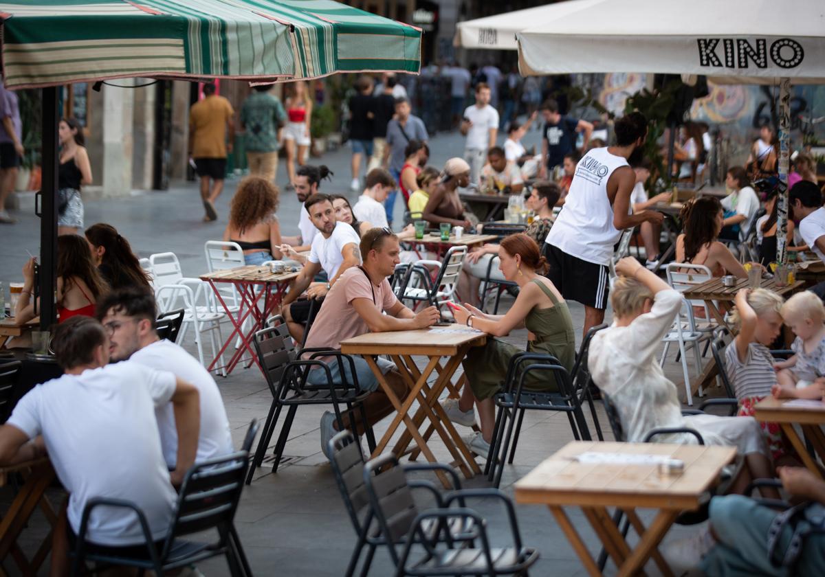 Varias personas sentadas en terrazas en la plaza dels Àngels del Raval, en Barcelona