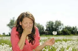 Mujer estornuda en el campo a causa de la alergia.