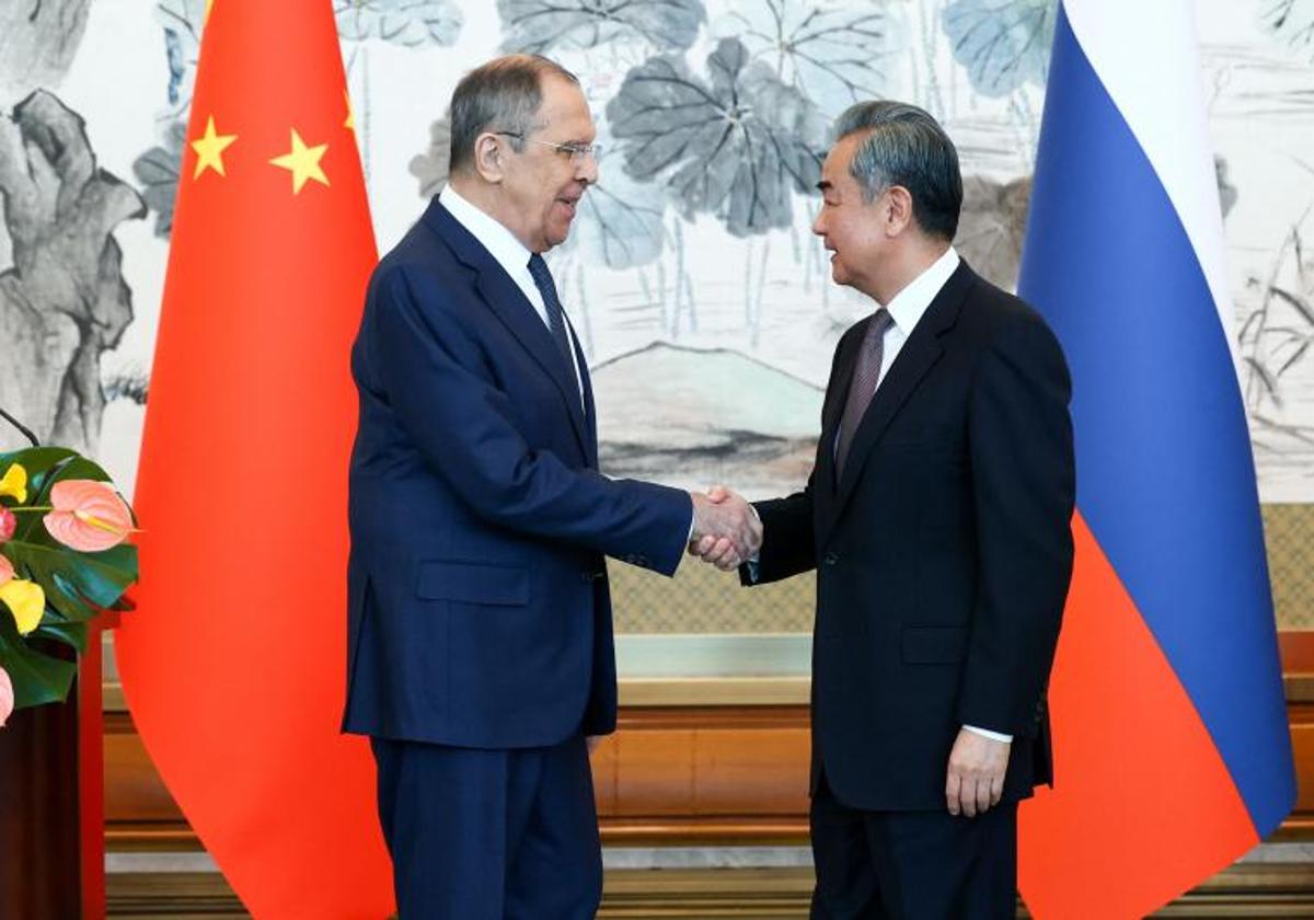 El ministro de Exteriores chino, Wang Yi, estrecha la mano a su homólogo ruso, este martes en Pekín.