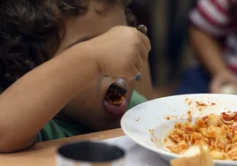 Un niño come durante el almuerzo un plato de pasta.