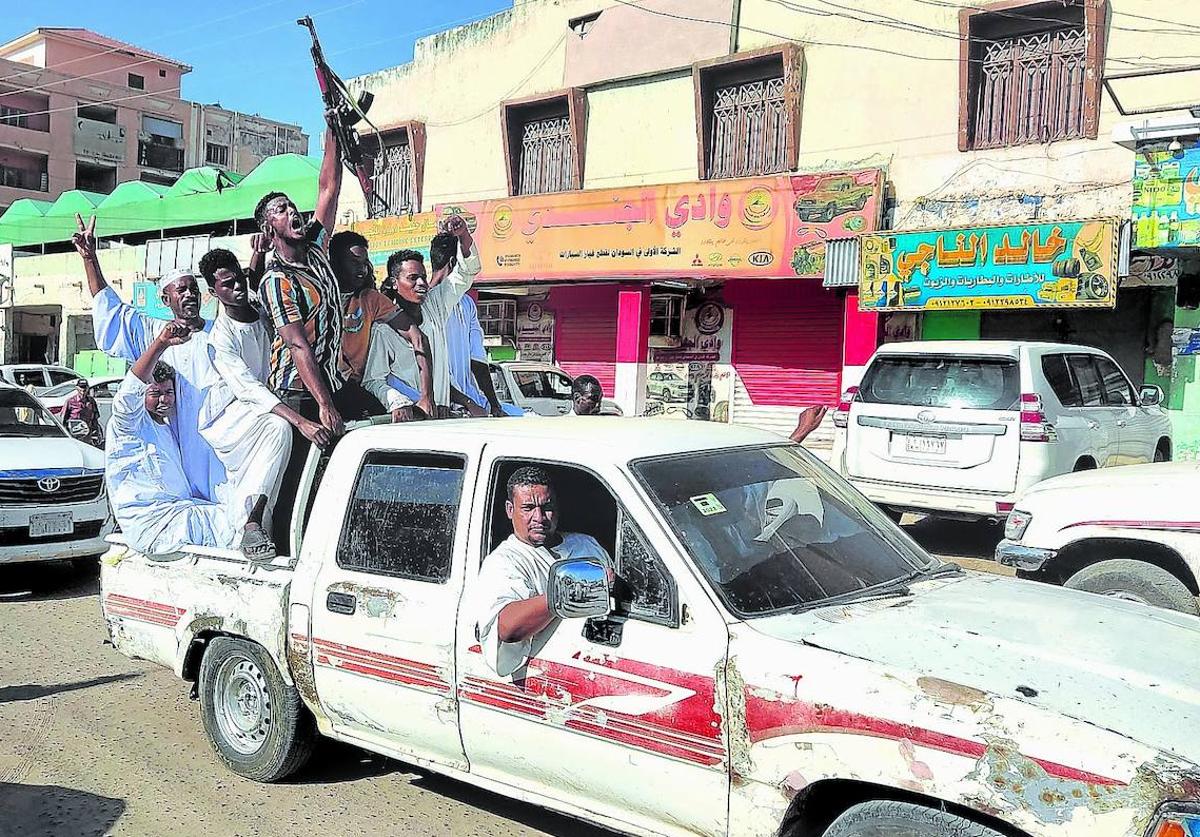 Sudaneses cantan consignas mientras conducen por una calle para expresar su apoyo al ejército en la ciudad de Gadaref, en el Sudán devastado por la guerra.