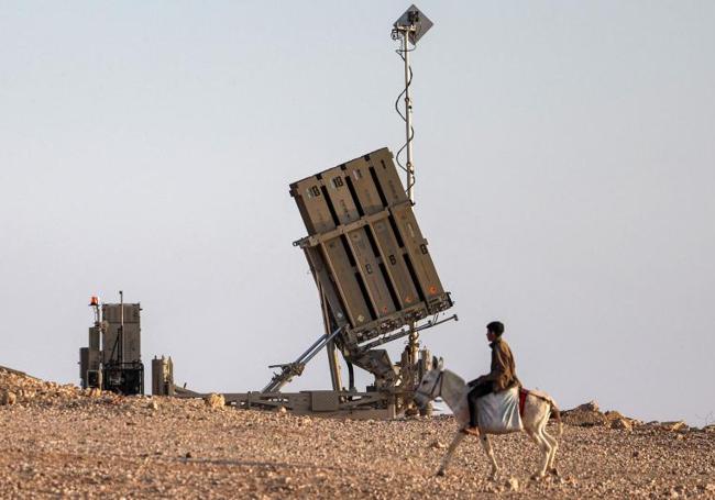 Un hombre y su burro, ante una batería de defensa israelí.