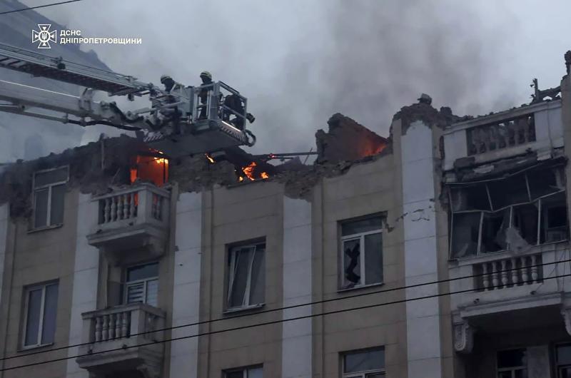 Los bomberos trabajan para apagar el fuego en un edificio golpeado por un misil.