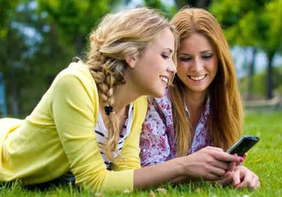 Dos adolescentes mirando un móvil.