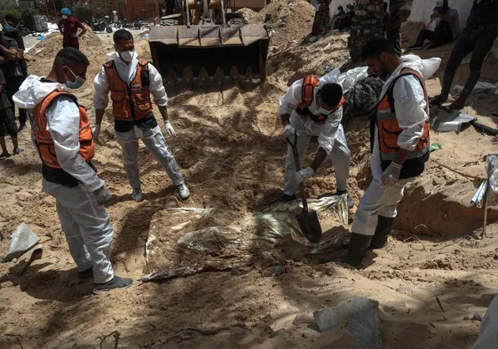 Los equipos de defensa civil excavan en una fosa común localizada en las instalaciones del hospital Nasser.