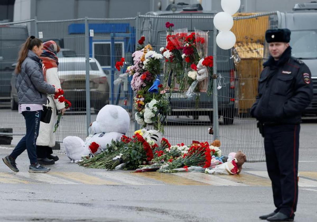 Dos jóvenes depositan flores en un memorial improvisado en recuerdo a las víctimas del ataque terrorista en el Crocus City Hall