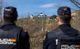 Dos agentes de la Policía Nacional observan el vuelo de un helicóptero