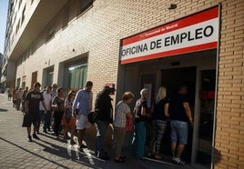 Un grupo de parados haciendo cola para entrar en una oficina de empleo.