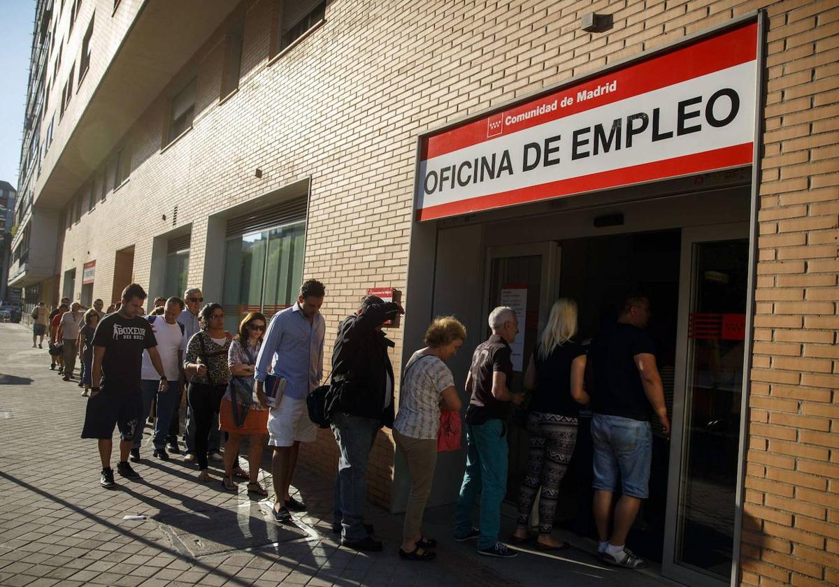 Un grupo de parados haciendo cola para entrar en una oficina de empleo.