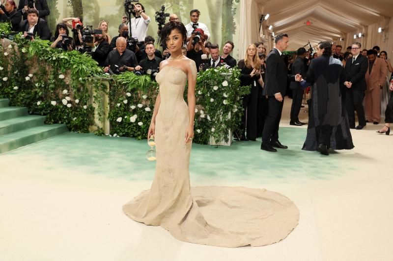 La cantante Tyla con un sugerente vestido de Balmain a lo reloj de arena, como su bolso de mano, tan entallado que para subir las escaleras tuvo que ser llevada en brazos. Maravilloso el detalle de la arena recorriendo sus brazos. 