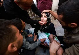 Una madre recibe el auxilio de la gente tras perder a su hijo en un bombardeo.