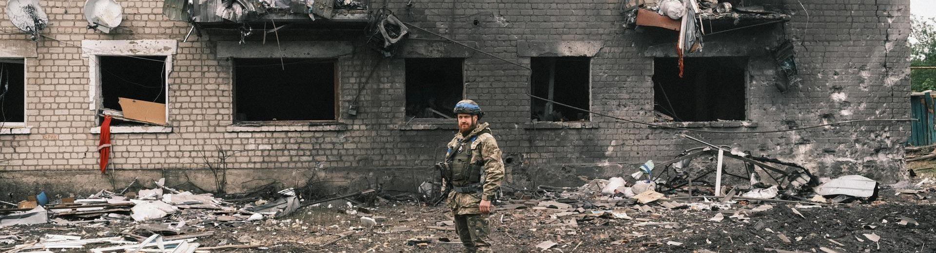 Un militar posa ante los restos carbonizados de un edificio en la periferia de Járkov.