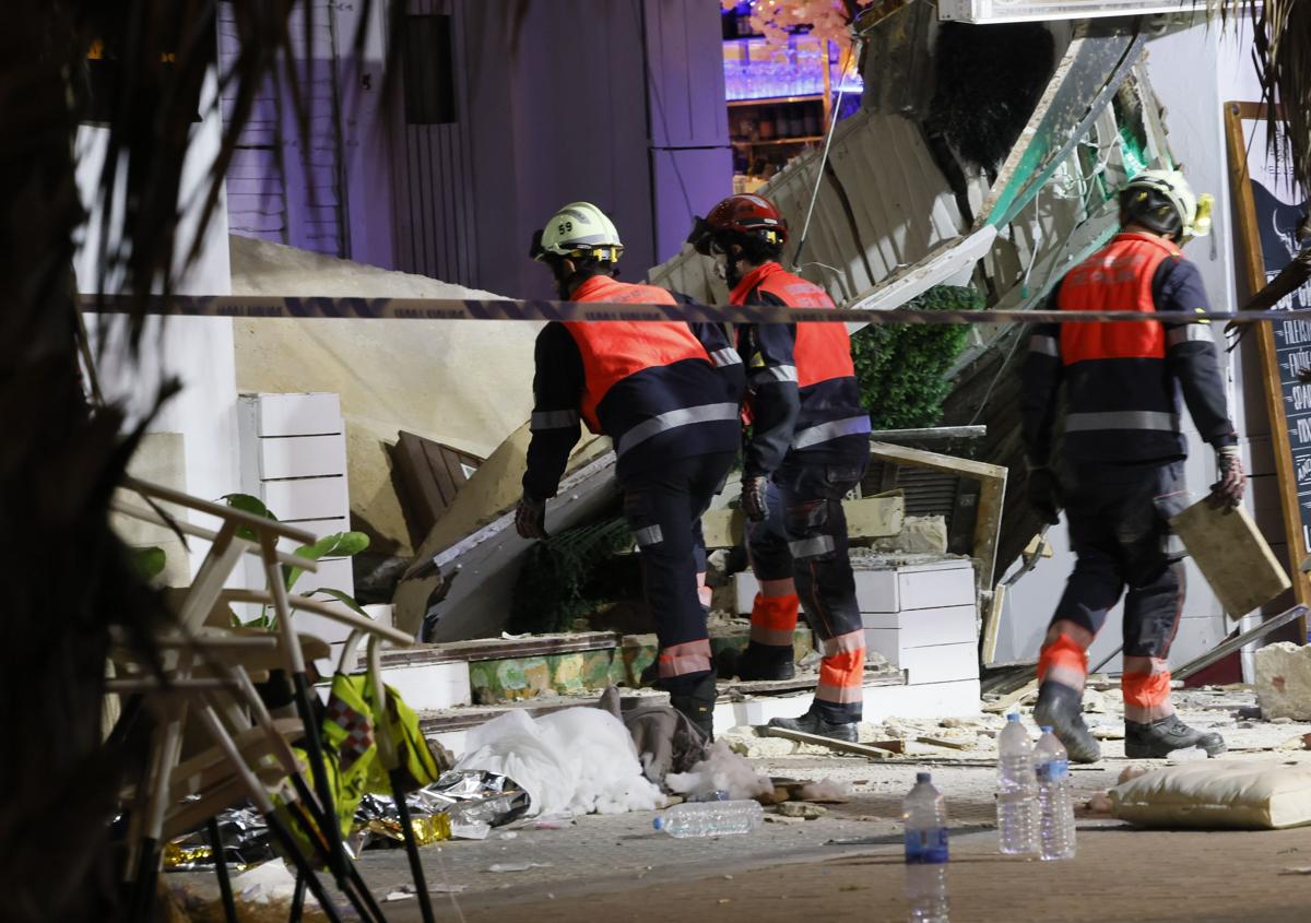 Imagen secundaria 1 - En la imagen superior, vista del edificio donde estaba el restaurante siniestrado; debajo, los técnicos de emergencias tratan de acceder al interior del local; por último, los sanitarios atienden a uno de los heridos.