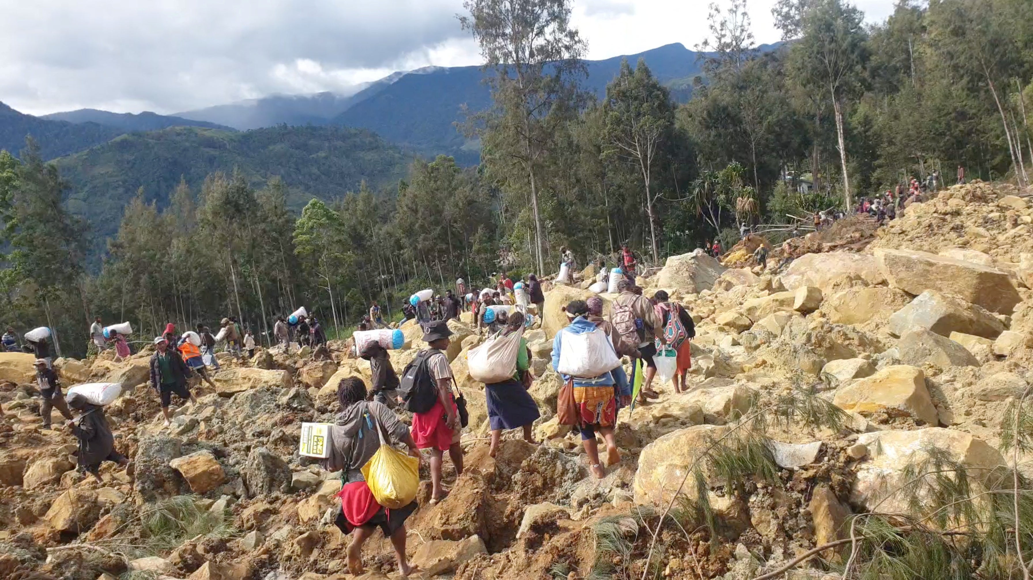 Habitantes de la zona tratan de recuperar algunos enseres sobre las rocas y la tierra.