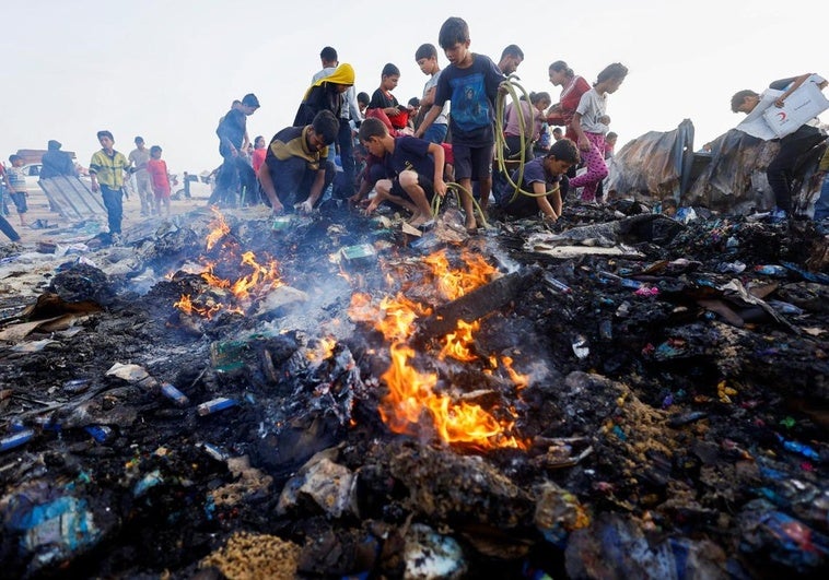 Un grupo de palestinos, entre ellos varios niños, busca entre los restos del campamento cuando todavía el fuego no se había extinguido.