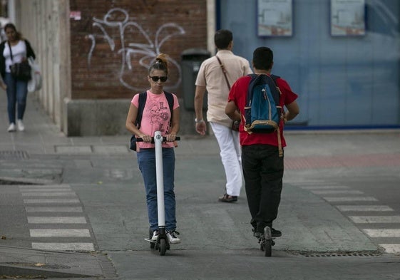 Personas circulando con un patinete eléctrico.