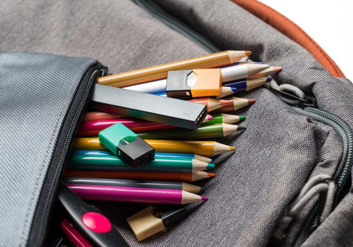 Un cigarrillo electrónico y recargas sobre las pinturas de un estuche escolar.