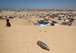 Un proyectil sin explotar yace a escasos metros de un niño en el campo de refugiados palestinos en Rafah.