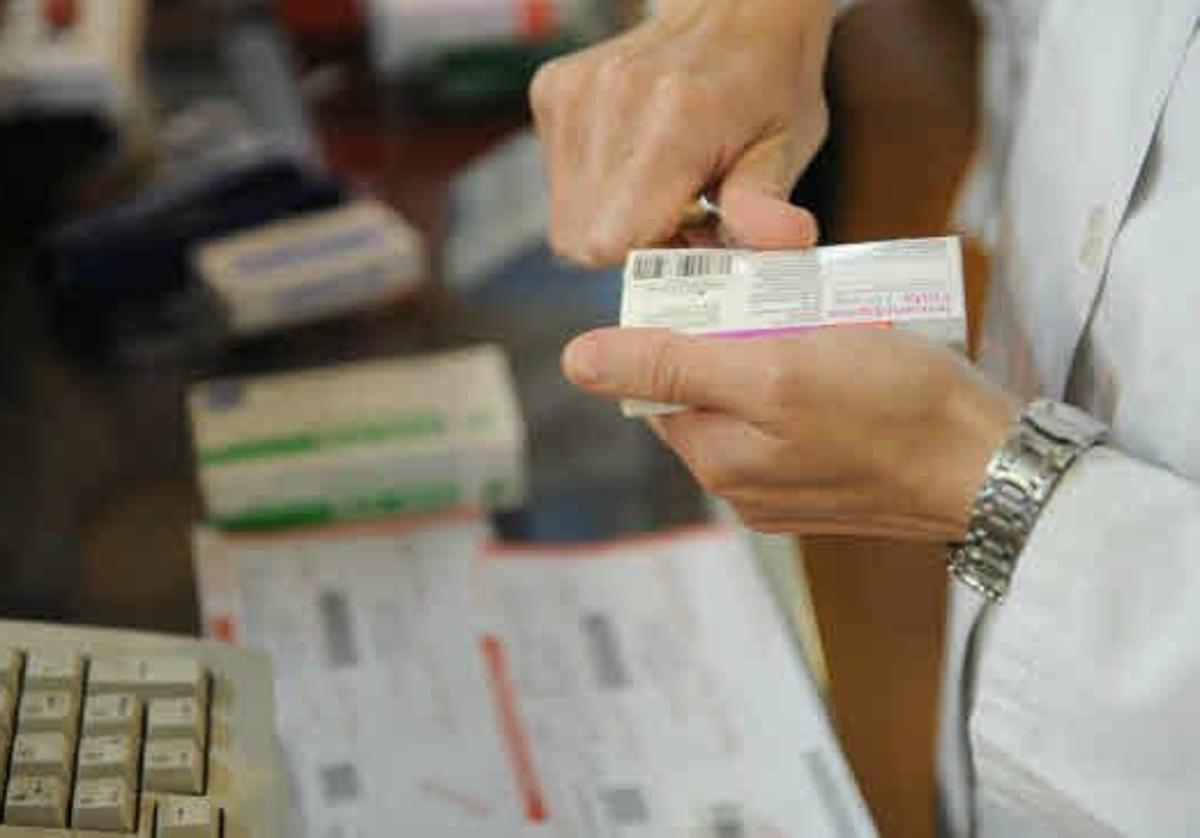 Farmacéutico corta el cupón precinto de una caja de medicamentos.