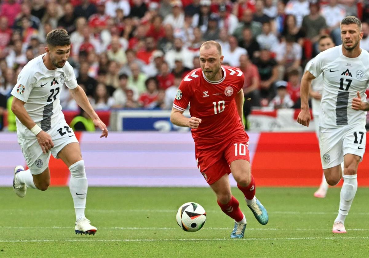 Christian Eriksen conduce la pelota ante la presencia de dos jugadores de Eslovenia.