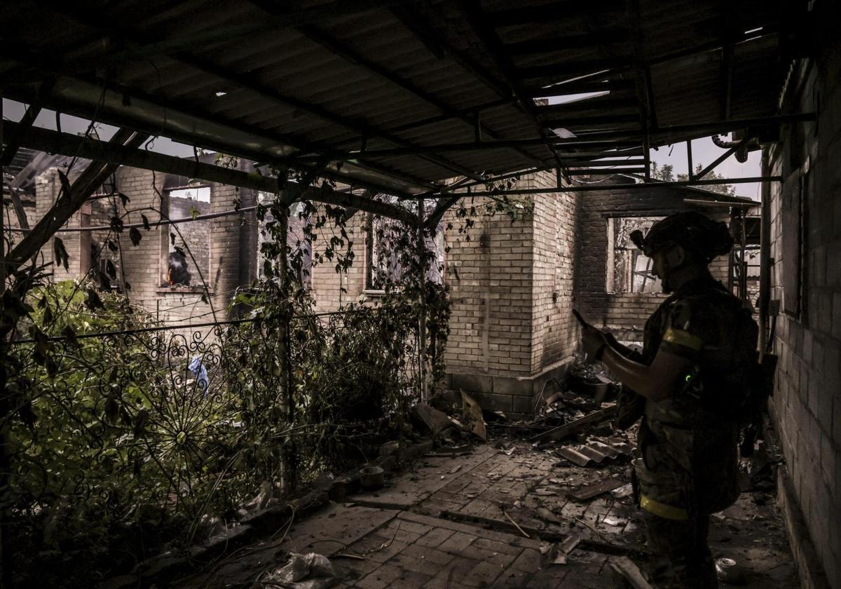 Un militar ucraniano mira su teléfono móvil dentro de un edificio destruido.