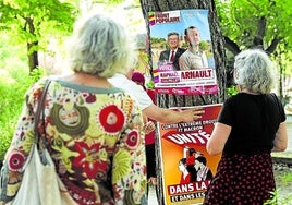 Varios ciudadanos observan carteles del Nuevo Frente Popular, la coalición de izquierdas.