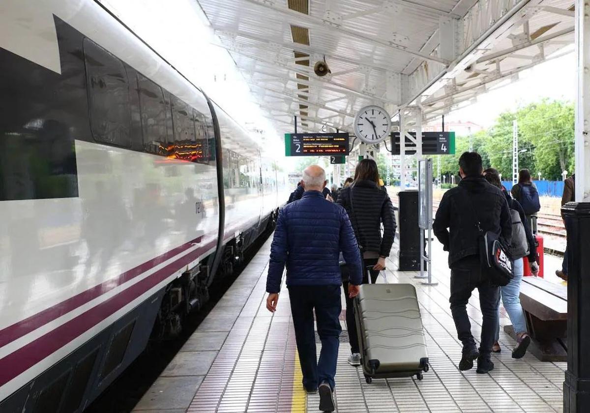 Pasajeros con sus maletas por una estación de tren.