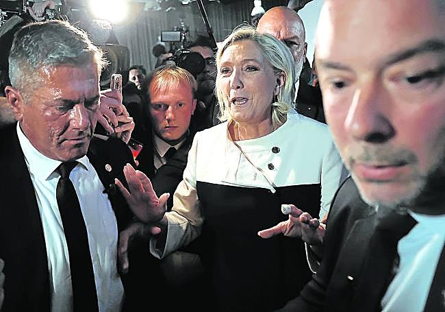 Marine Le Pen hace un gesto de calma entre los rostros preocupados de sus compañeros ante los resultados de los primeros sondeos.