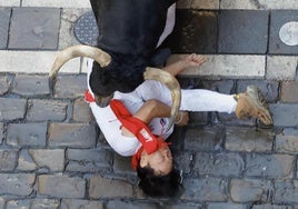 Un mozo acorralado por uno de los toros de la ganadería La Palmosilla en el encierro de este domingo.