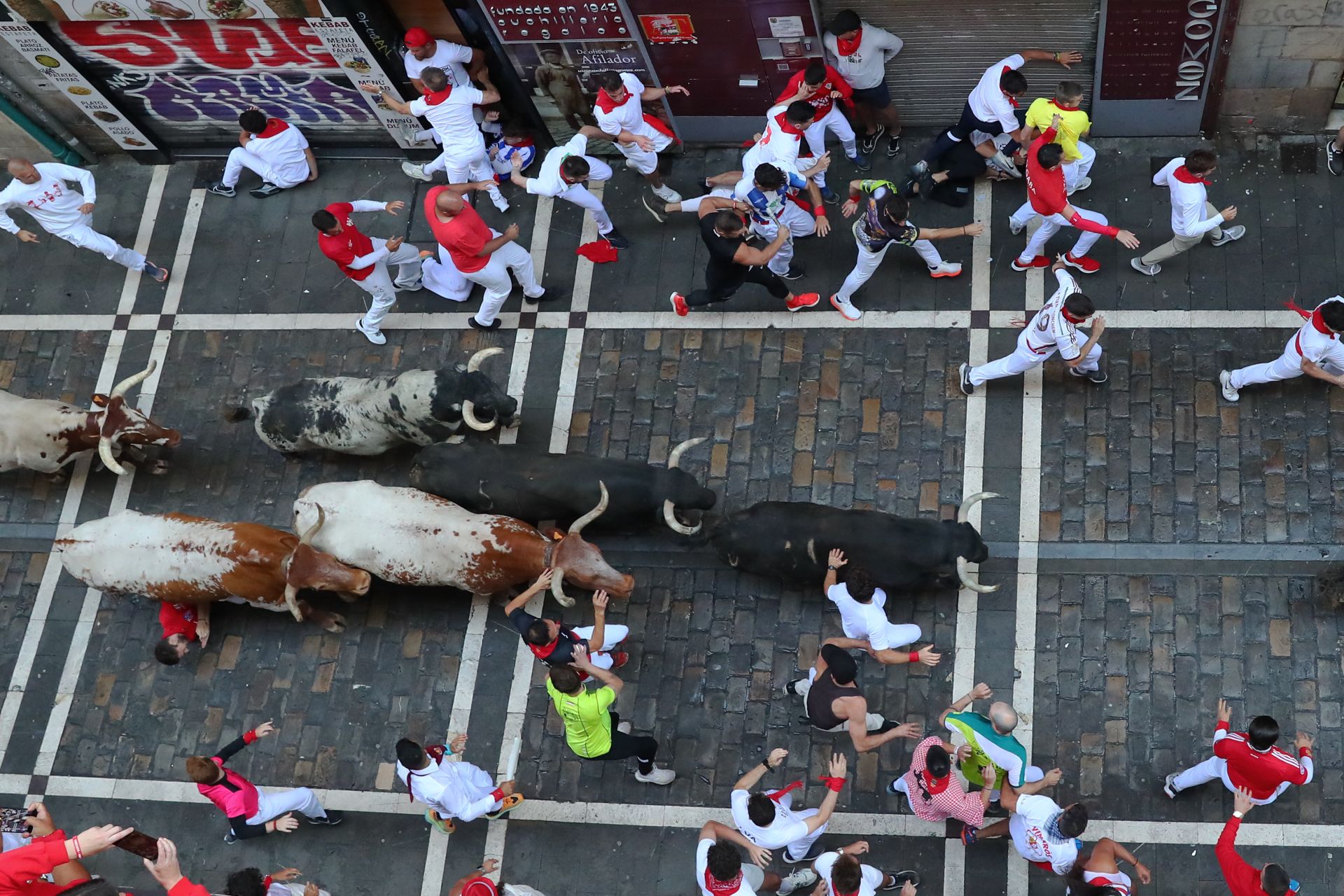 Varios mozos son perseguidos en el tramo inicial de la calle Estafeta desde la curva de Mercaderes durante el segundo encierro de los Sanfermines protagonizados por la ganadería de los Herederos de D. José Cebada Gago, de Medina Sidonia (Cádiz).