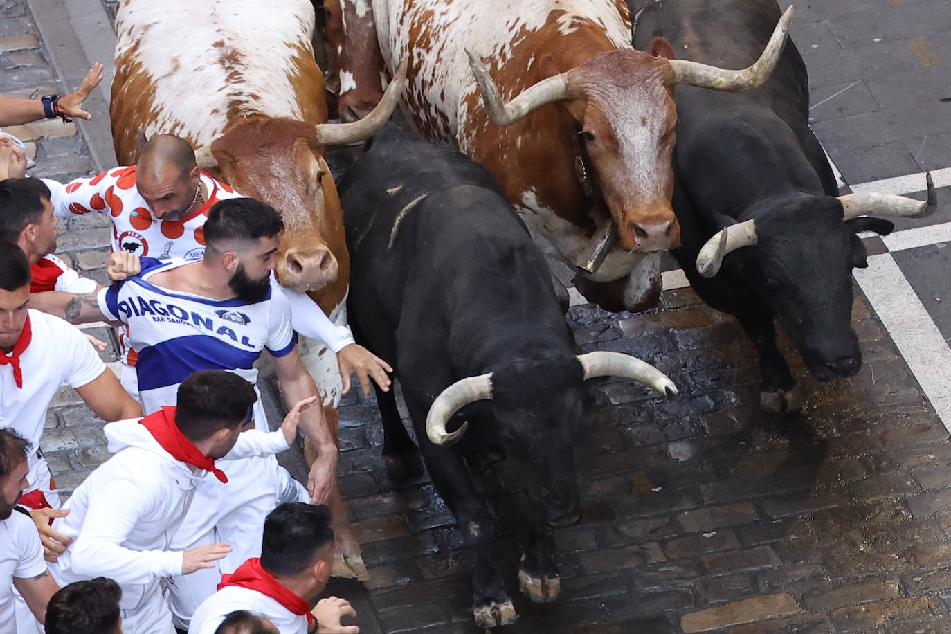 Varios mozos son perseguidos en el tramo inicial de la calle Estafeta desde la curva de Mercaderes durante el segundo encierro de los Sanfermines.