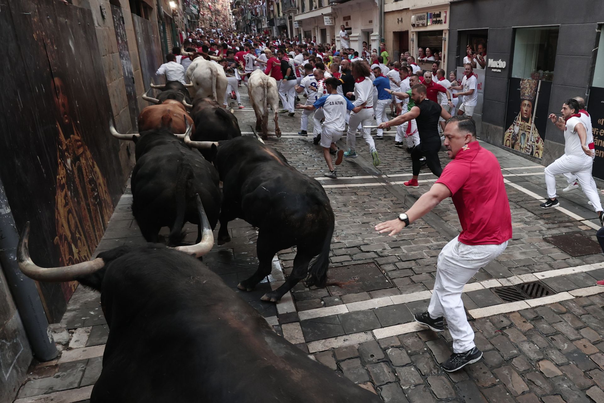 Los toros de la ganadería de Fuente Ymbro pasan por la curva de Mercaderes y enfilan la calle de la Estafeta en el cuarto encierro de los Sanfermines.