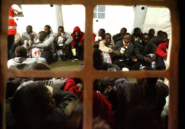 Inmigrantes descansan en un recinto del puerto de Los Cristianos, en Tenerife, tras ser interceptados en un cayuco.