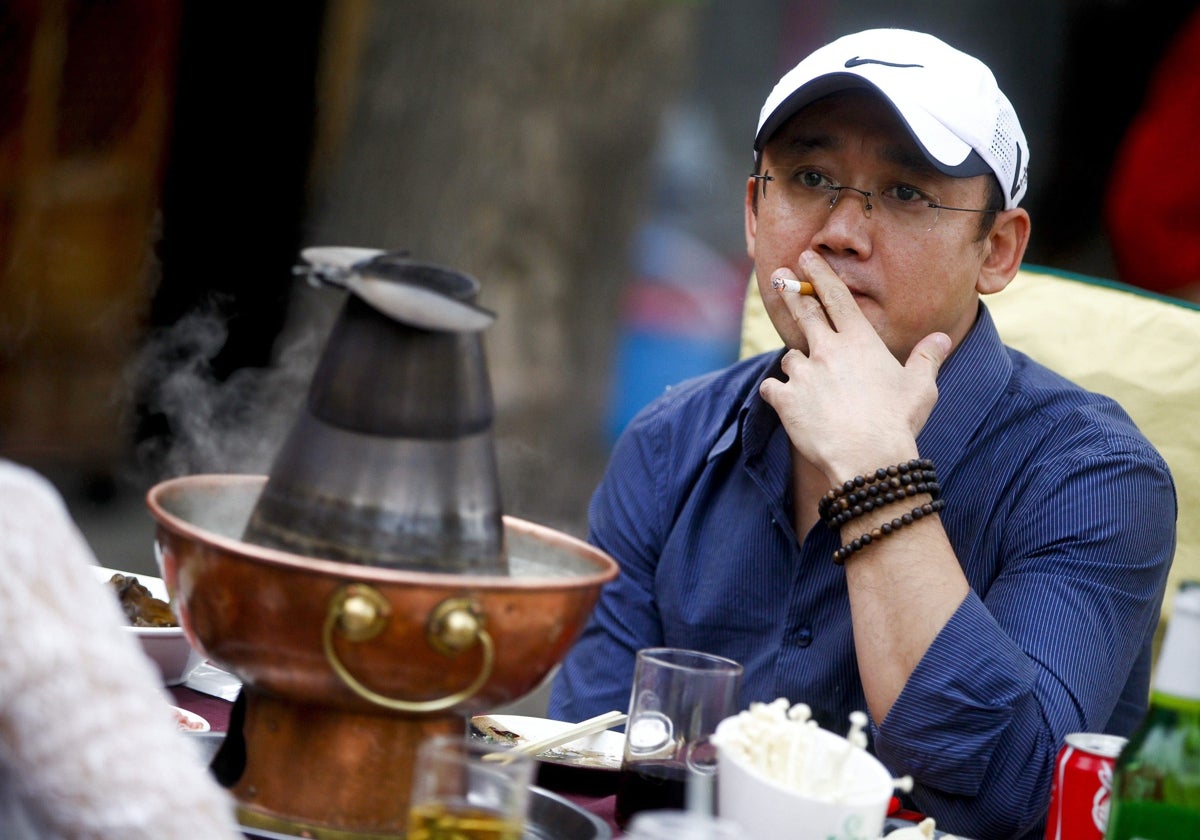 Un hombre fuma un cigarrillo sentado en la terraza de un restaurante.