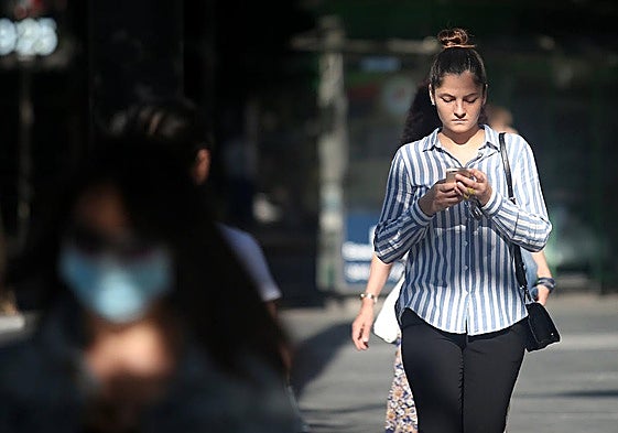 Una joven camina con su móvil.