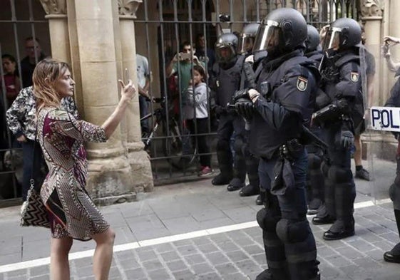 Una mujer fotografía a los antidisturbios de la Policía Nacional en Pamplona