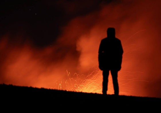 Una persona observa el Etna en erupción.