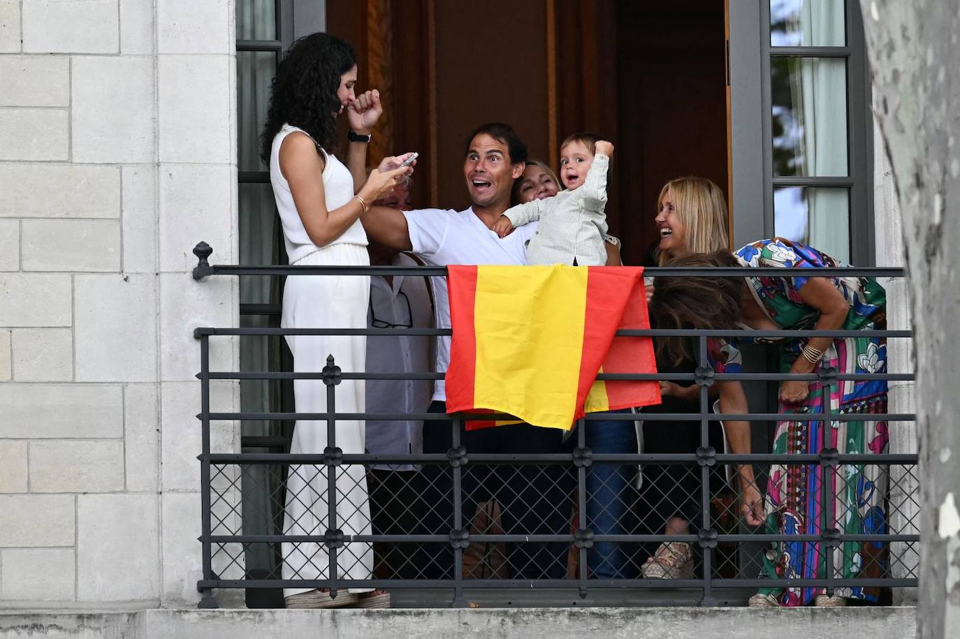 El tenista Rafa Nadal y su familia ven la ceremonia desde un balcón.