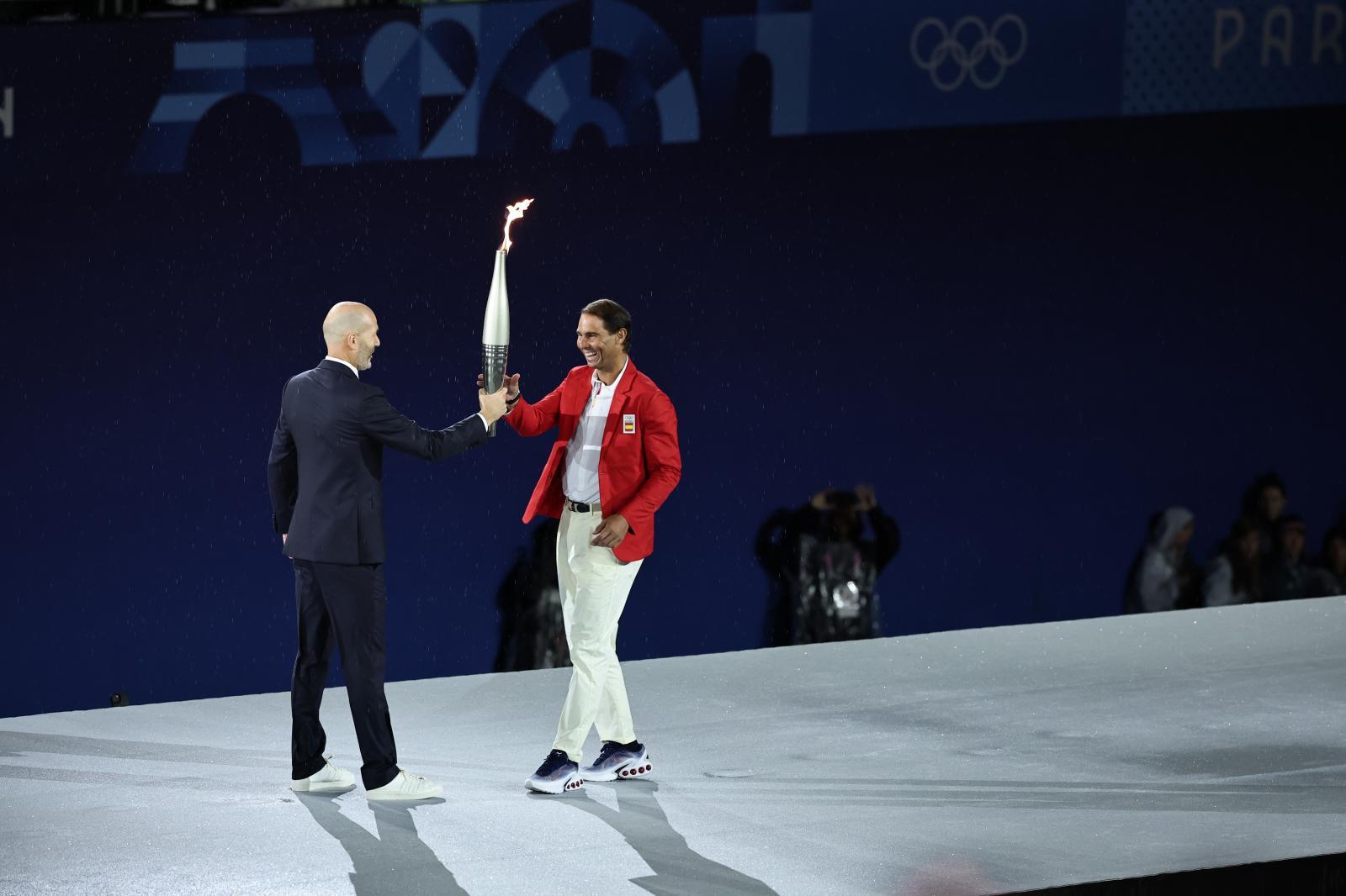 Zinedine Zidane entrega la antorcha olímpica a Rafael Nadal.