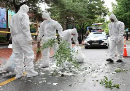 Barrenderos con traje de protección para guerra química y biológica recogiendo basura norcoreana en Corea del Sur.