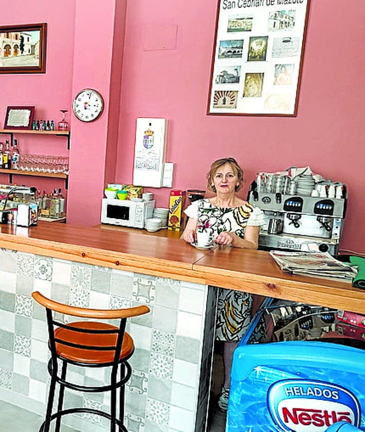 Imagen secundaria 2 - De arriba a abajo: Una mujer toma un refresco en el bar de Jairo, el único de Bayubas de Abajo, un pueblo de Soria de 150 lugareños. Vecinos de Bayubas charlan a las puertas de la taberna. Yolanda, en su bar de San Cebrián de Mazote, otro pequeño pueblo de cien habitantes en Valladolid. 