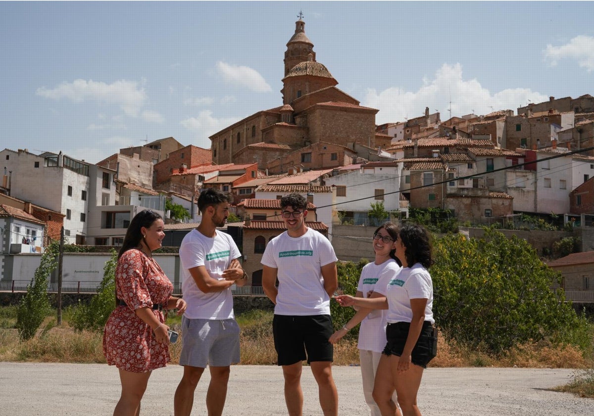 Imagen principal - De arriba a abajo: Los cinco jóvenes universitarios con Oliete y su iglesia de la Asunción al fondo; almazara de donde cada año salen cien mil litros de aceite de los olivos recuperados por Apadrina un olivo; uno de los árboles con el QR que permite a su padrino o madrina seguir su evolución y sus cuidados.