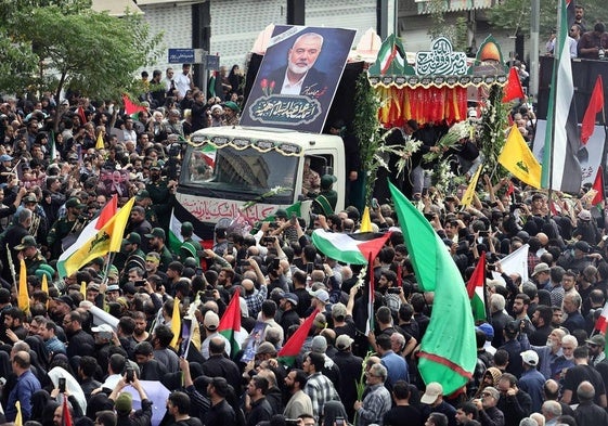 Un camión adornado con flores traslada el ataúd de Ismail Haniyeh por las calles de Teherán.