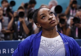 Simones Biles, muy seria, observando las puntuaciones tras su mal ejercicio.