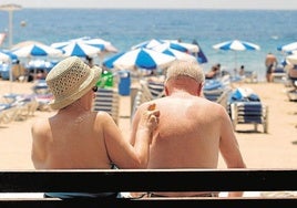 Una pareja de turistas se protege del sol con crema solar en la playa.