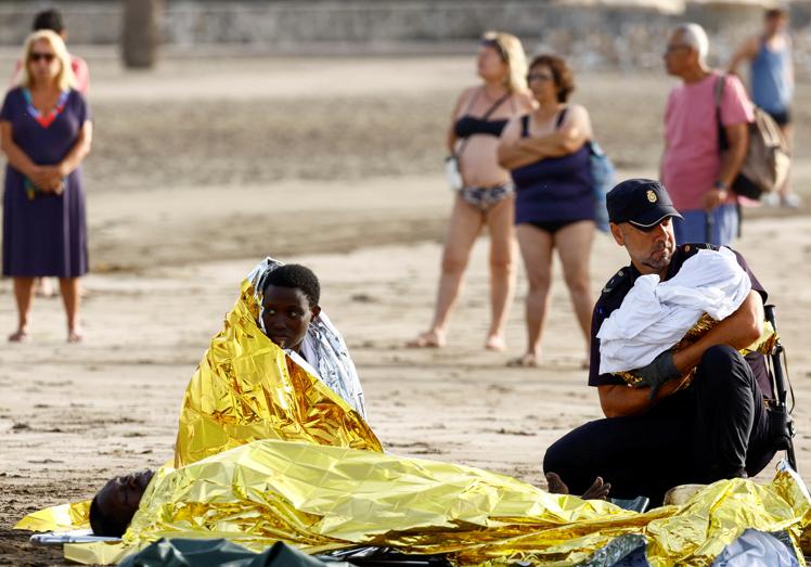 Un policía nacional atiende a un bebé llegado a la playa de Las Burras, en Gran Canaria, el pasado mes de julio.