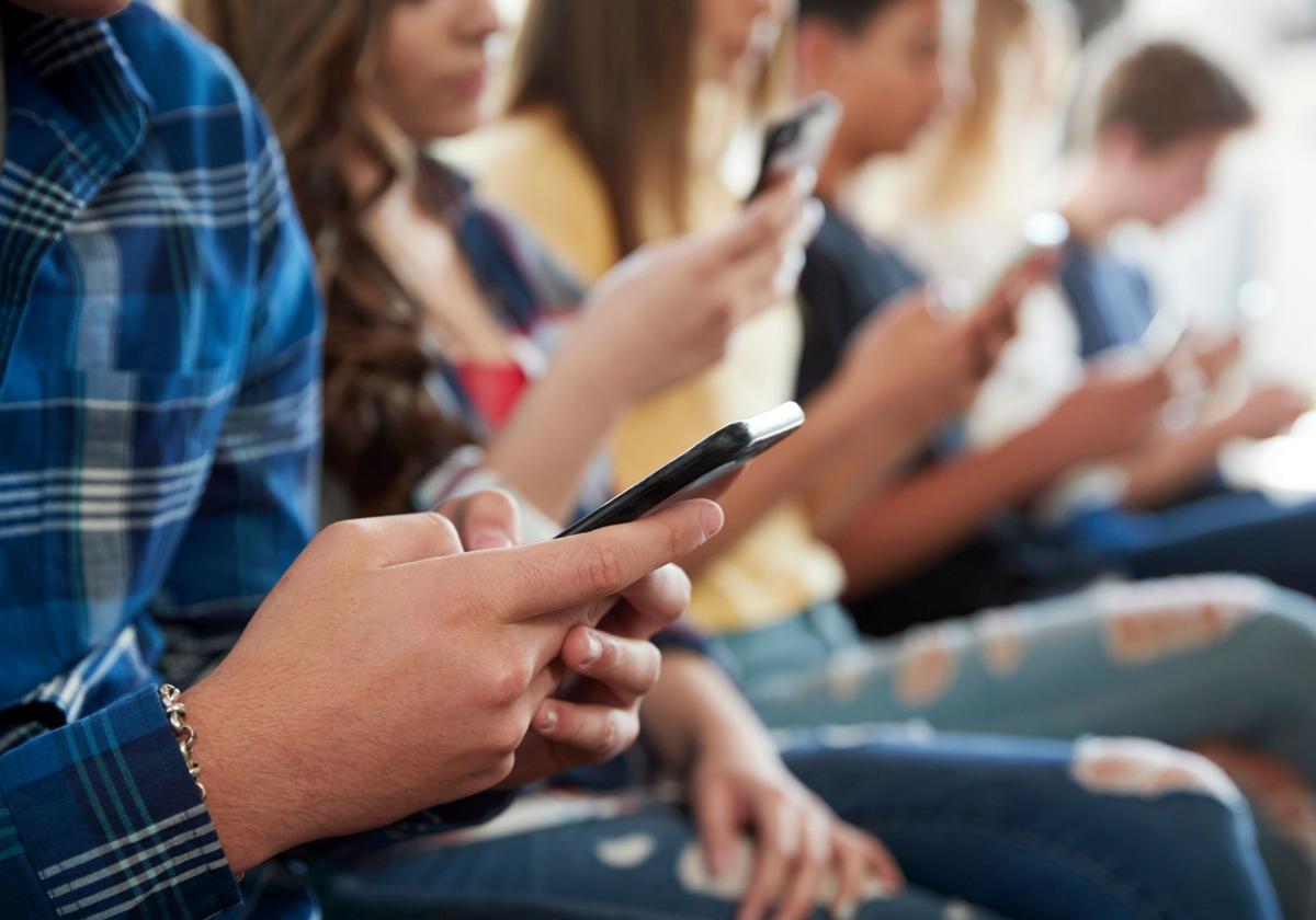 Un grupo de jóvenes utiliza sus teléfonos móviles.